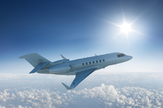 Private jet  flying above the clouds with the sun in blue sky