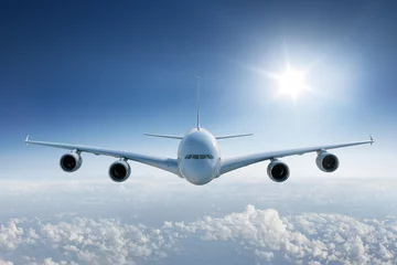 Foto op Plexiglas Groot vliegtuig dat boven de wolken vliegt, naar de camera met de zon in de blauwe lucht © Karsten