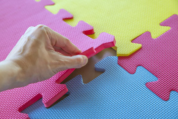 Close up of a joining parts of the colorful pieces of a children's soft toy mat and fitness gym