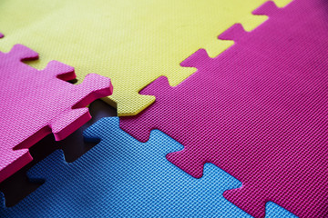 Close up of a joining parts of the colorful pieces of a children's soft toy mat and fitness gym