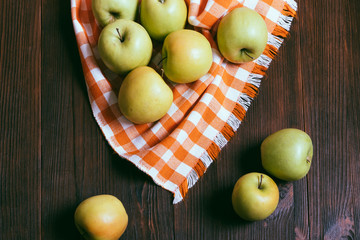 Top view of green apples on a wooden table and orange checkered