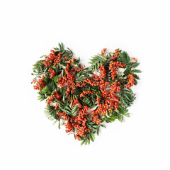 Heart symbol made of rowan on white background. flat lay, top view. autumn wallpaper