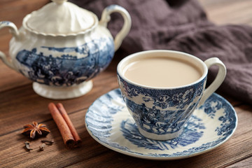 Milk tea chai latte refreshing organic healthy traditional hot beverage drink with natural aroma spices blend in porcelain cup on wooden table background