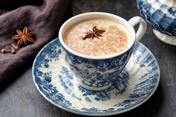 Milk tea chai latte refreshing morning organic healthy traditional hot beverage drink with natural aroma spices blend in porcelain cup on wooden table background
