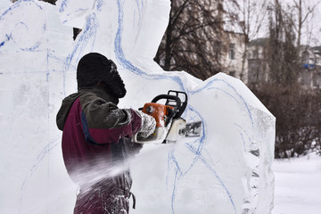Worker using chainsaw carving an ice sculpture