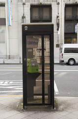 Public telephone on pathway beside traffic road for people use p