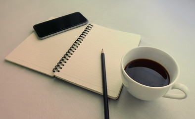 Coffee in white cup with Journal book and smart phone