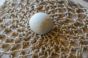 Ancient elevator rope basket with orbed stone net load spread on wooden floor. St. Trinity Meteora...