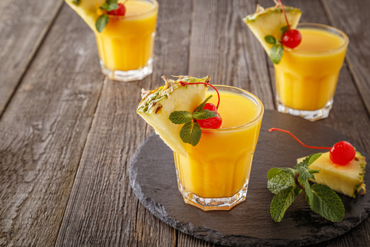 Glasses of pineapple juice with pieces of pineapple