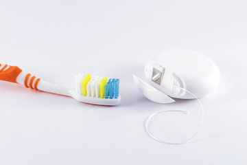 Toothbrush and dental floss on white background