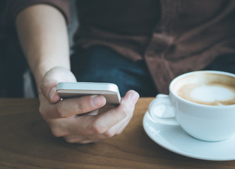 Businessman use mobile phone and coffee cup dark tone.