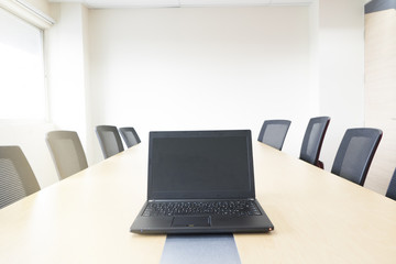 laptop on wooden table in meeting room white board sunlight from window