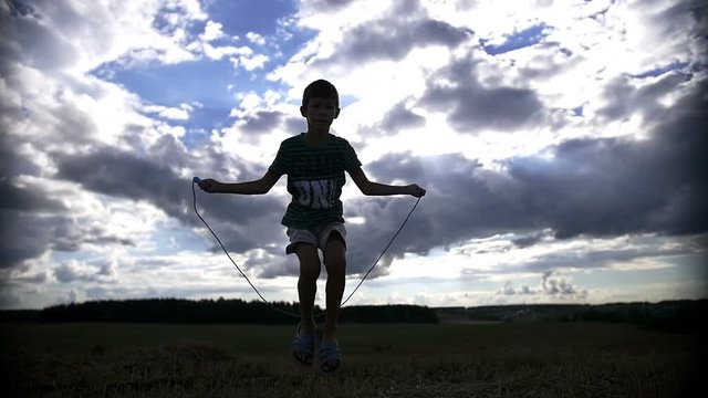 silhouette of a boy jumping rope on the sky background