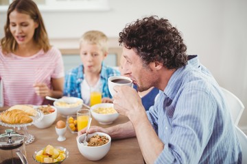 Obraz na płótnie Canvas Man drinking tea during breakfast with family