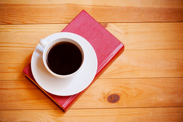 Coffee cup and book on wooden  background. Top view
