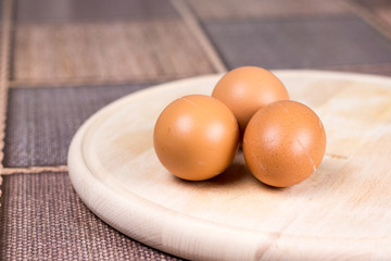 Three raw domestic chicken eggs on the wooden board
