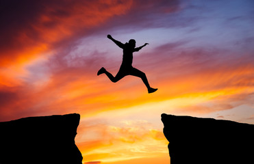 Man jumping across the gap from one rock to cling to the other.