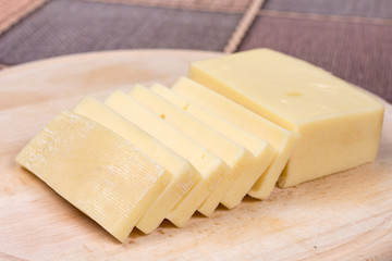 Sliced yellow pizza cheese on the wooden cutting board