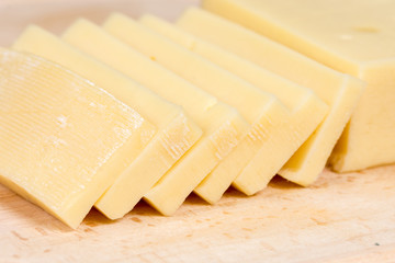 Sliced yellow cheese on the kitchen cutting board
