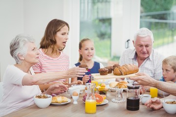 Obraz na płótnie Canvas Multi-generation family having muffins during breakfast