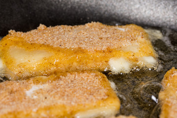 Frying fried yellow cheese with eggs in frying pan