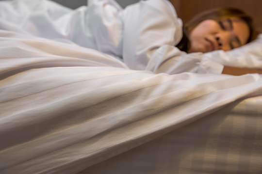 Asian Woman Sleeping In Bed. Focus On Bed Sheets