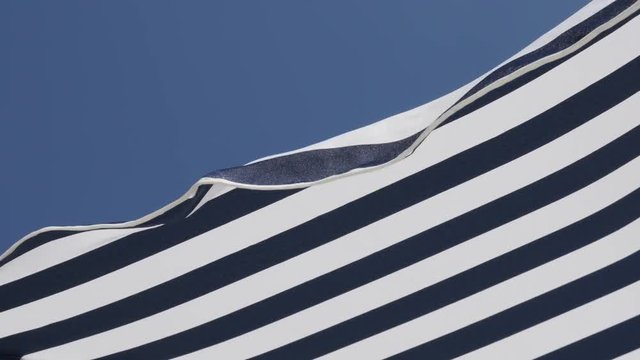 Fabric of umbrella made for protection from the sun slow motion 1080p FullHD footage - Beach striped blue parasol against clear sky moving on wind slow-mo 1920X1080 HD video 
