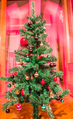 Artificial Christmas tree with colorful ornaments on red background 