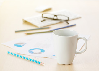 Office workplace with coffee, supplies and reports