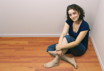 Fototapeta na wymiar young girl brunette sitting onrange wooden floor barefoot