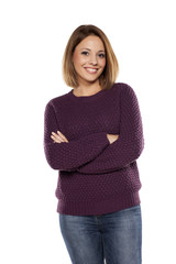 young happy woman in a purple sweater and jeans with crossed arms