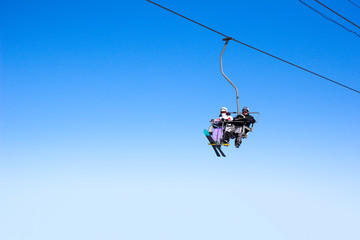 Ski lift chairs with skiers isolated on a blue sky