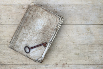 Rusty key on the old tattered book
