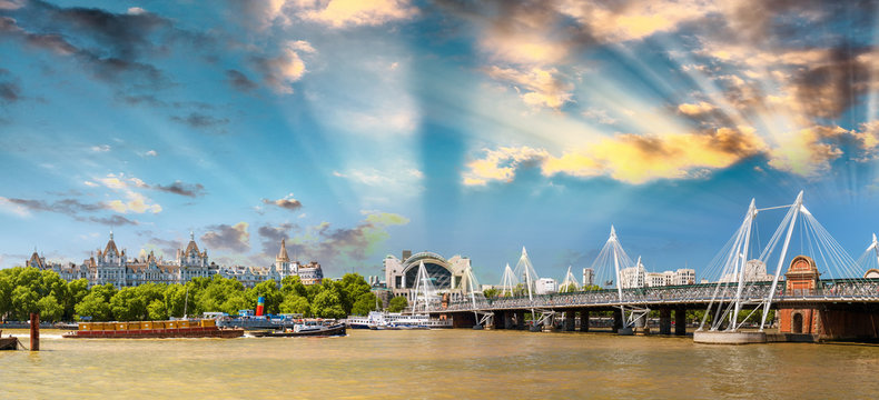 Hungerford Bridge at sunset with city skyline along Thames, Lond