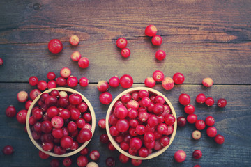 Fresh red forest cranberry in a round bowls on a wooden table surface. Autumn harvest of wild berries