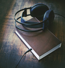 Books and headphones on wooden surface grunge. Concept of listening to audiobooks.