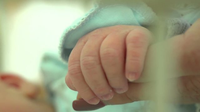 Mother touches the hand of her newborn son, close up
