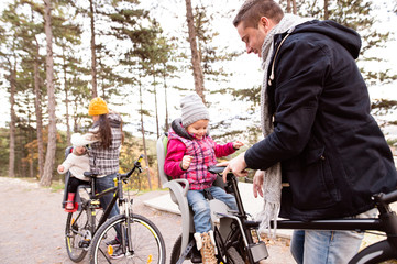 Fototapeta premium Young family in warm clothes cycling in autumn park