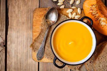 Bowl of pumpkin soup on rustic wooden background