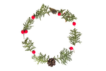Christmas frame made of green thuja twigs, pine cones and red wild rose fruits on white background. Top view, flat lay. Copy space for text