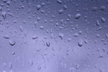 Water drops against blue background, wet glass surface car.