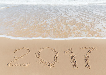 Fototapeta na wymiar New 2017 Year sign on a sea coast sand