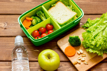 lunch box for kid with fresh vegetables on wooden background