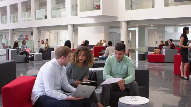 Student group studying together in a busy modern university lobby, shot on R3D