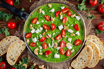 Vegetable Green Omelette with tomatoes, kale, greek cheese, olives, nuts, toast on wooden background. concept healthy food