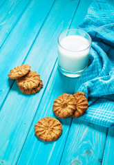 Cup of milk and cookies on a blue wooden table.