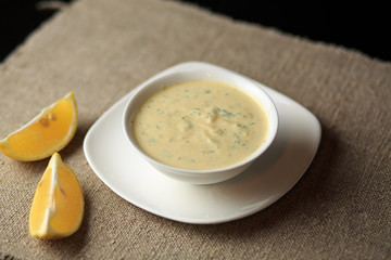 sauce in a plate, mayonnaise in a plate, home-made sauce, sauce Caesar, a lemon, greens