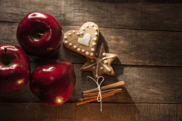 Gingerbread winter cookies with red apples and cinnamon on a wooden table.