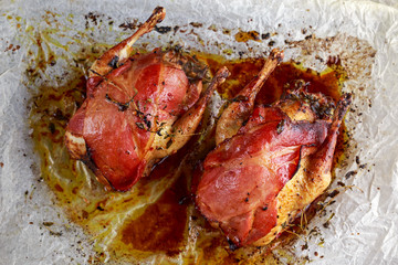 Ready to eat Roast partridges with bacon on crumpled paper.