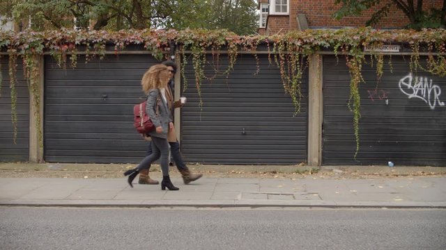 Stylish Young Couple Walking Past Garages On City Street